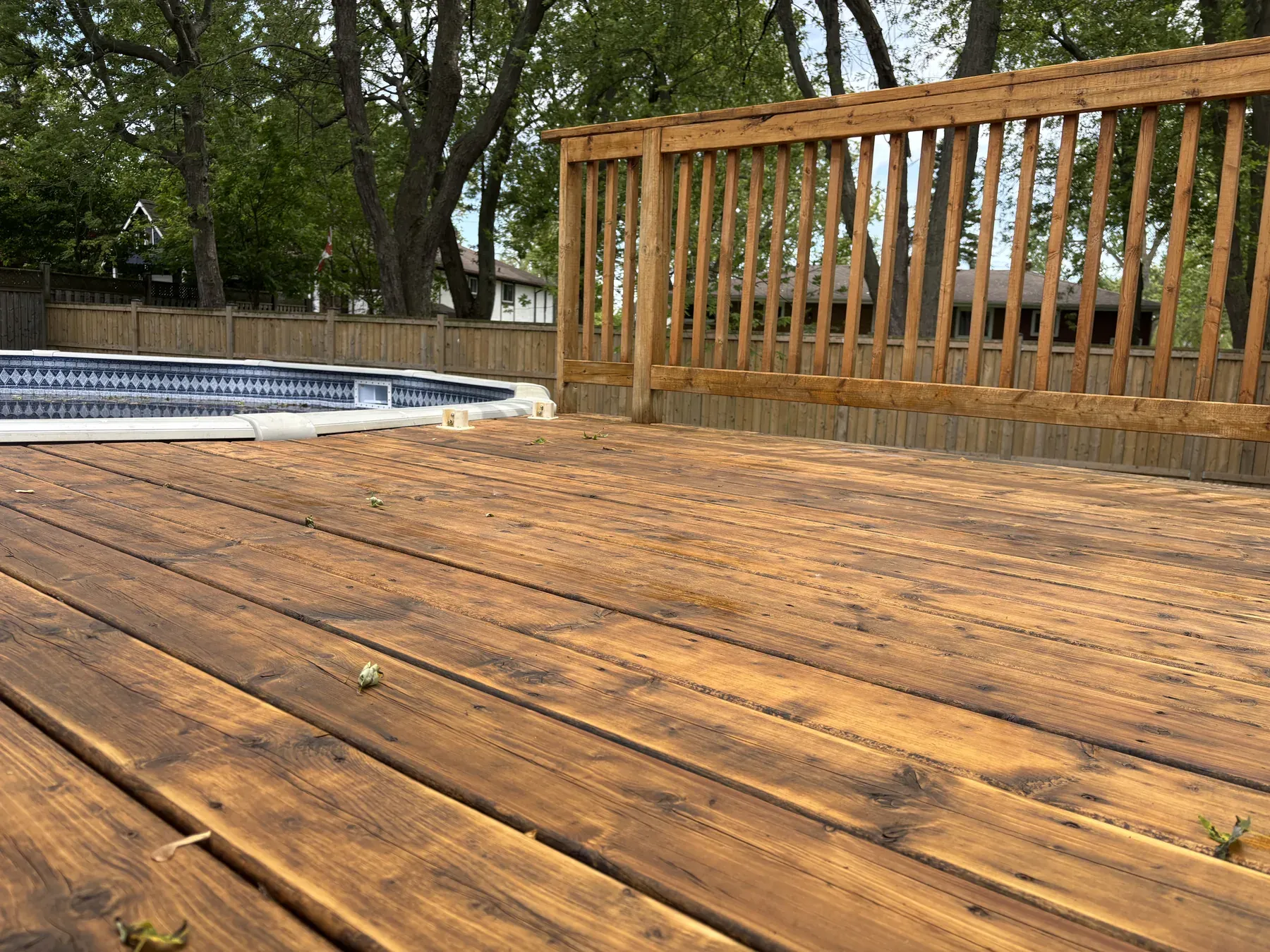 Fort Erie deck after maintenance recoat — box steps and black aluminum spindle railings